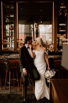 a bride and groom standing in front of a bar with their backs to each other