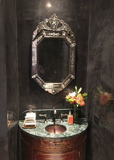 a bathroom with a sink, mirror and flowers on the counter in front of it