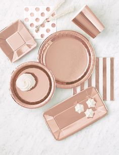 rose gold party plates, napkins and condiments are laid out on a marble surface