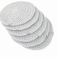 four crocheted coasters sitting on top of each other in grey and white