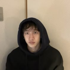 a young man wearing a black hoodie and looking at the camera