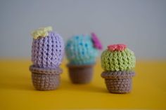 three small crocheted ice cream cones sitting next to each other on a yellow surface