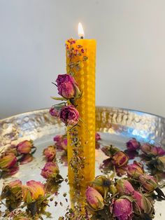 a candle that is sitting in some kind of bowl with flowers on it and water