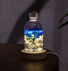 a glass bottle filled with blue and yellow flowers sitting on top of a wooden table