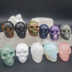 six different colored skulls sitting next to each other on top of a rock with crystals