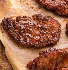 three pieces of meat sitting on top of a wooden cutting board