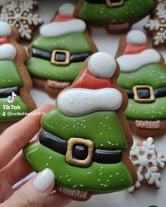 decorated christmas cookies in the shape of santa's hats are being held by a woman