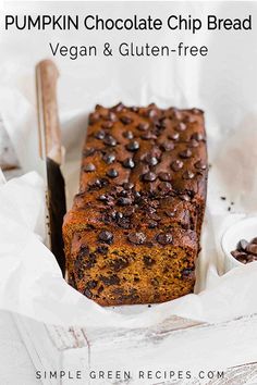 a loaf of chocolate chip banana bread in a white box next to a knife and spoon