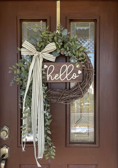 a wreath with the word hello is hanging on a door