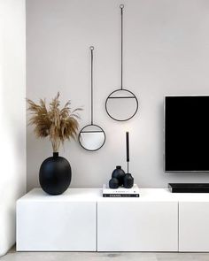 a tv sitting on top of a white shelf next to a vase filled with plants