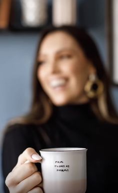 a woman holding a white coffee cup in her right hand