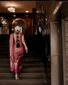 a woman is walking down the stairs in a red dress and white headpieces