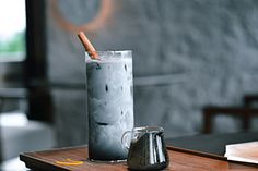 a glass filled with liquid sitting on top of a table next to a coffee pot