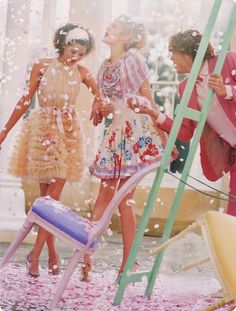 three women are standing in front of a ladder and confetti