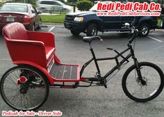 a red and black bike with a side car attached to it in a parking lot