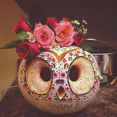 a pumpkin decorated with flowers and an owl face