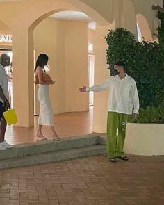 two people are standing in front of a building and one is holding a yellow bag