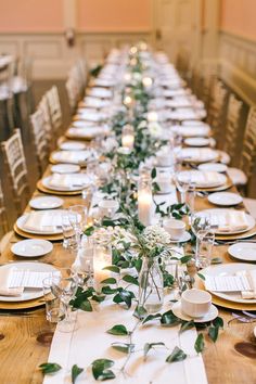 the long table is set with white plates and place settings