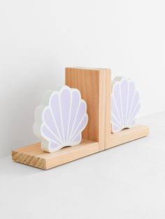 two white seashells are sitting on a wooden stand