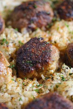 some meatballs and rice in a pan with seasoning sprinkled on top