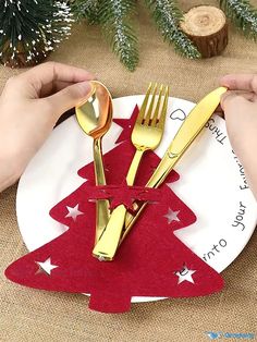 two hands holding forks and spoons over a paper plate with a christmas tree on it