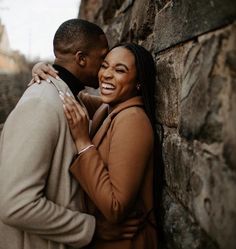 a man and woman hugging against a stone wall