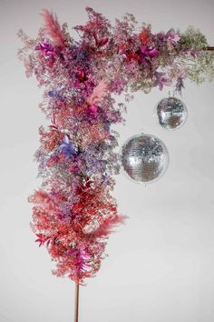 two disco balls are hanging from a tree with pink and purple flowers on it's branches