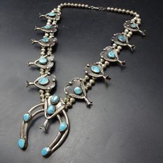 OLD PAWN SQUASH BLOSSOM NECKLACE DESCRIPTION: This exquisite necklace features gorgeous specimens of natural high blue turquoise set in heavy gauge vintage sterling silver. The tri-petal blossoms are adorned with plump applied raindrops and hand applied stampwork.  This exceptional necklace will be a valuable addition to your collection of fine vintage Southwestern and Native American jewelry. MEASUREMENTS:  Necklace measures 24" end to end Naja measures 2 3/4" x 2 1/4" Beads are securely strung Blue Sterling Silver Western Jewelry, Blue Western Sterling Silver Jewelry, Vintage Blue Turquoise Necklace Collectible, Collectible Vintage Blue Turquoise Necklace, Western Style Blue Turquoise Collectible Necklace, Western Style Turquoise Necklace Collectible, Collectible Western Silver Necklace, Antique Turquoise Jewelry For Jewelry Making, Vintage Blue Turquoise Necklace For Jewelry Making