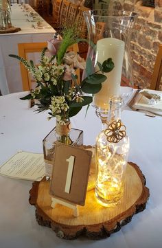 there is a vase with flowers in it on top of a wooden slice at the table