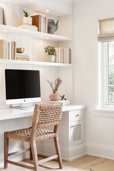 a white desk with a computer on top of it next to a chair and bookshelf