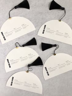 six black and white business cards with tags attached to them on a gray surface,