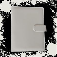 an empty white leather notebook on black and white paint splattered background