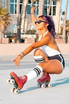 a woman riding a skateboard down a street next to palm trees and tall buildings