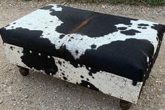 a black and white cow hide ottoman on wheels with studded metal trimmings