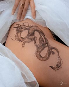 a woman's back with a dragon tattoo on her side and the bottom part of her stomach