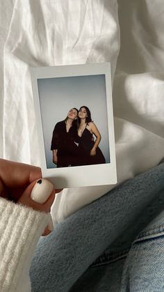 a woman holding up a polaroid with two women on it