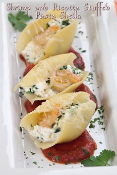 three stuffed shells on a white plate with parsley