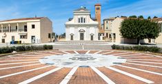 a clock tower in the middle of a courtyard surrounded by brick walkways and trees