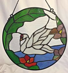 a stained glass window with a swan and flowers in the center, hanging on a chain