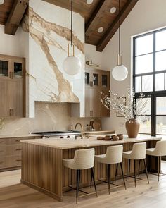 a large kitchen with wooden cabinets and white marble counter tops, along with modern pendant lights hanging from the ceiling