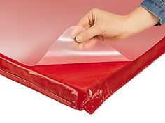 a person's hand on top of a red plastic sheet