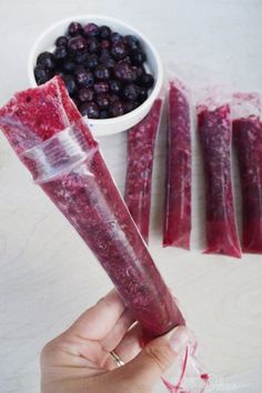 a person holding up a piece of food in front of blueberries and other foods