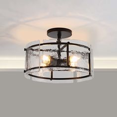 a semi flush light fixture with clear glass shades and black metal frame, hanging from the ceiling