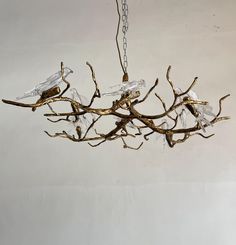 a chandelier made out of branches with glass birds on them hanging from the ceiling