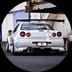 a white car parked in front of a building with its hood up and the back lights on