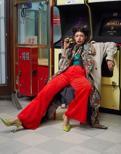 a woman is sitting on the floor in front of a bus and talking on her cell phone