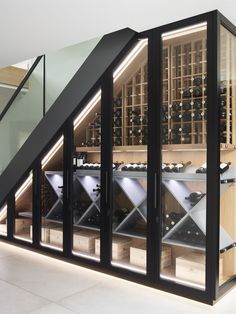 a wine cellar with many bottles in it and stairs leading up to the second floor