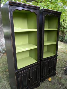 two black and green bookcases sitting in the grass