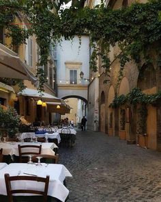 an alleyway with tables, chairs and umbrellas