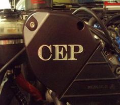 the cep logo is on the side of a car engine, with other cars in the background